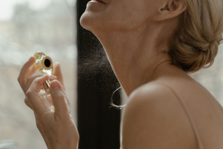 Femme vaporisant son parfum sur le cou près d'une fenêtre, lumière naturelle